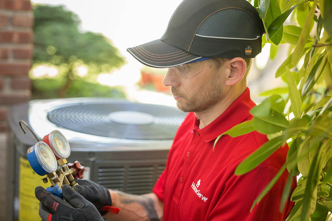 Close-up of man inspecting a tool near a heat pump unit