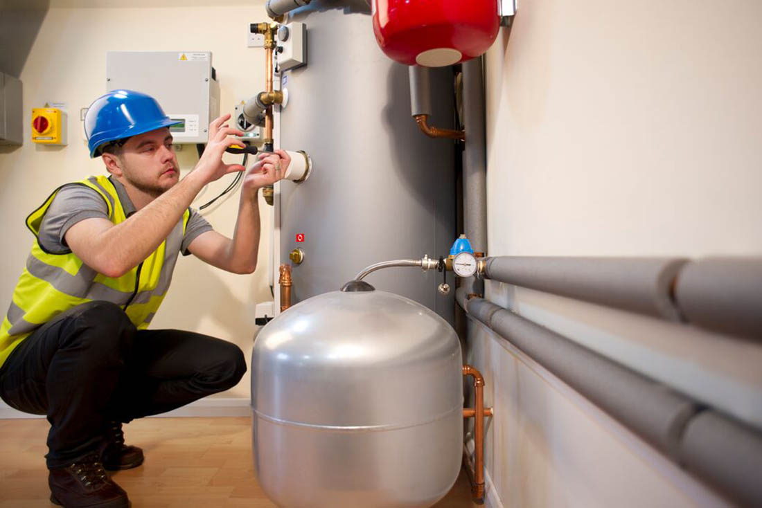 Service technician performing maintenance service on a tank water heater