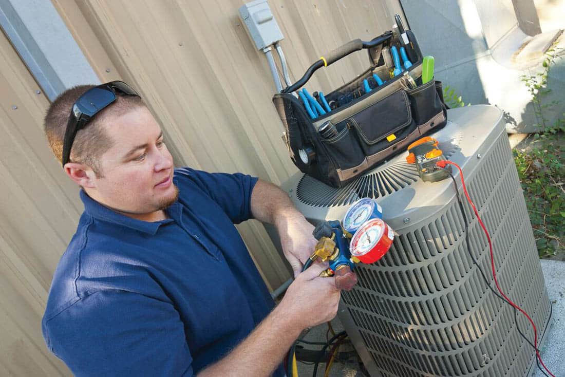 heatPumps-HeatPumpMaintenance-Supporting-1100×734 Man performing a heat pump maintenance test with tools resting on unit
